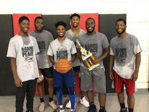 A group of young men posing after with a trophy and basketball.